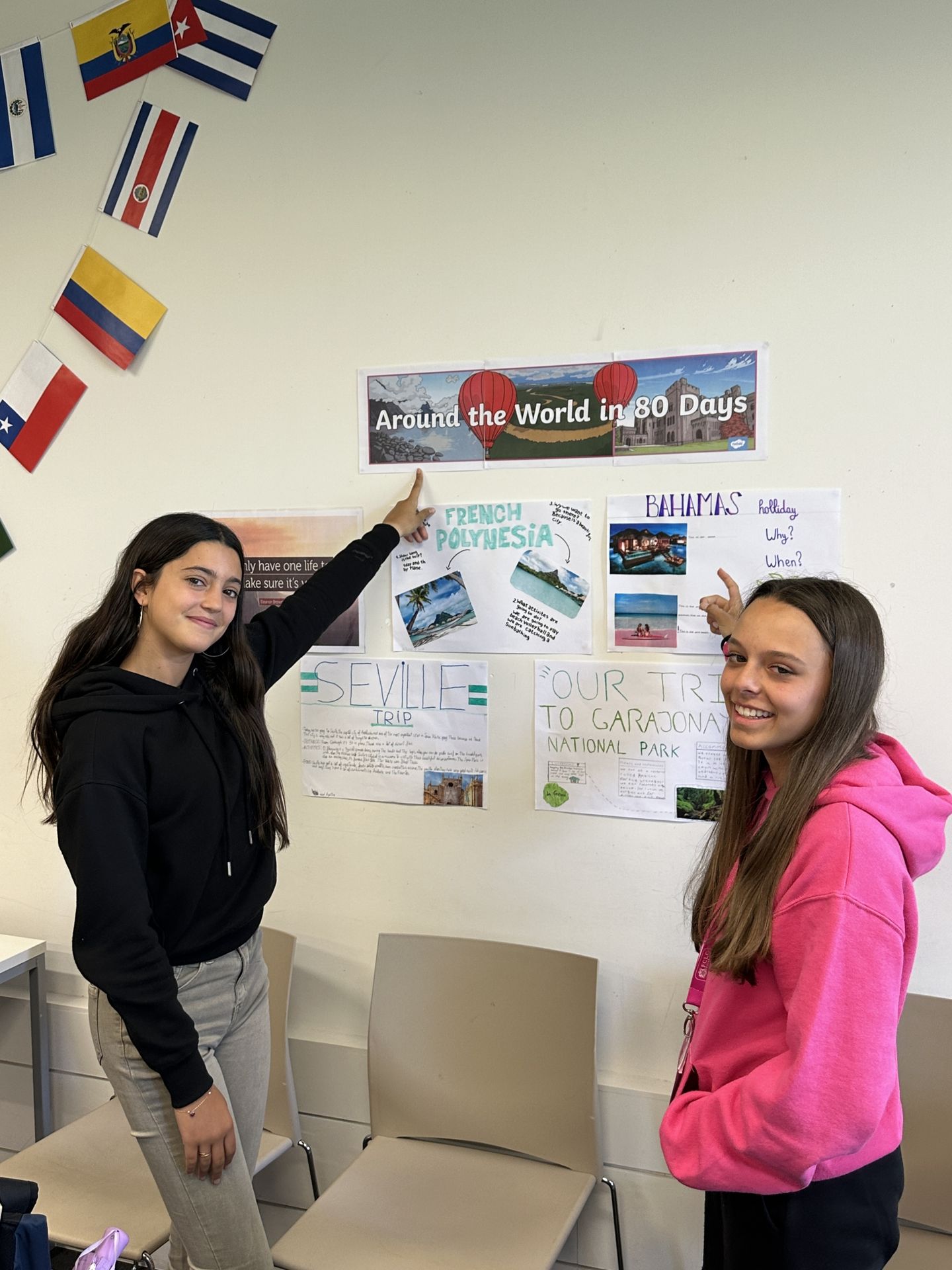Image of two students pointing to a poster made on the wall