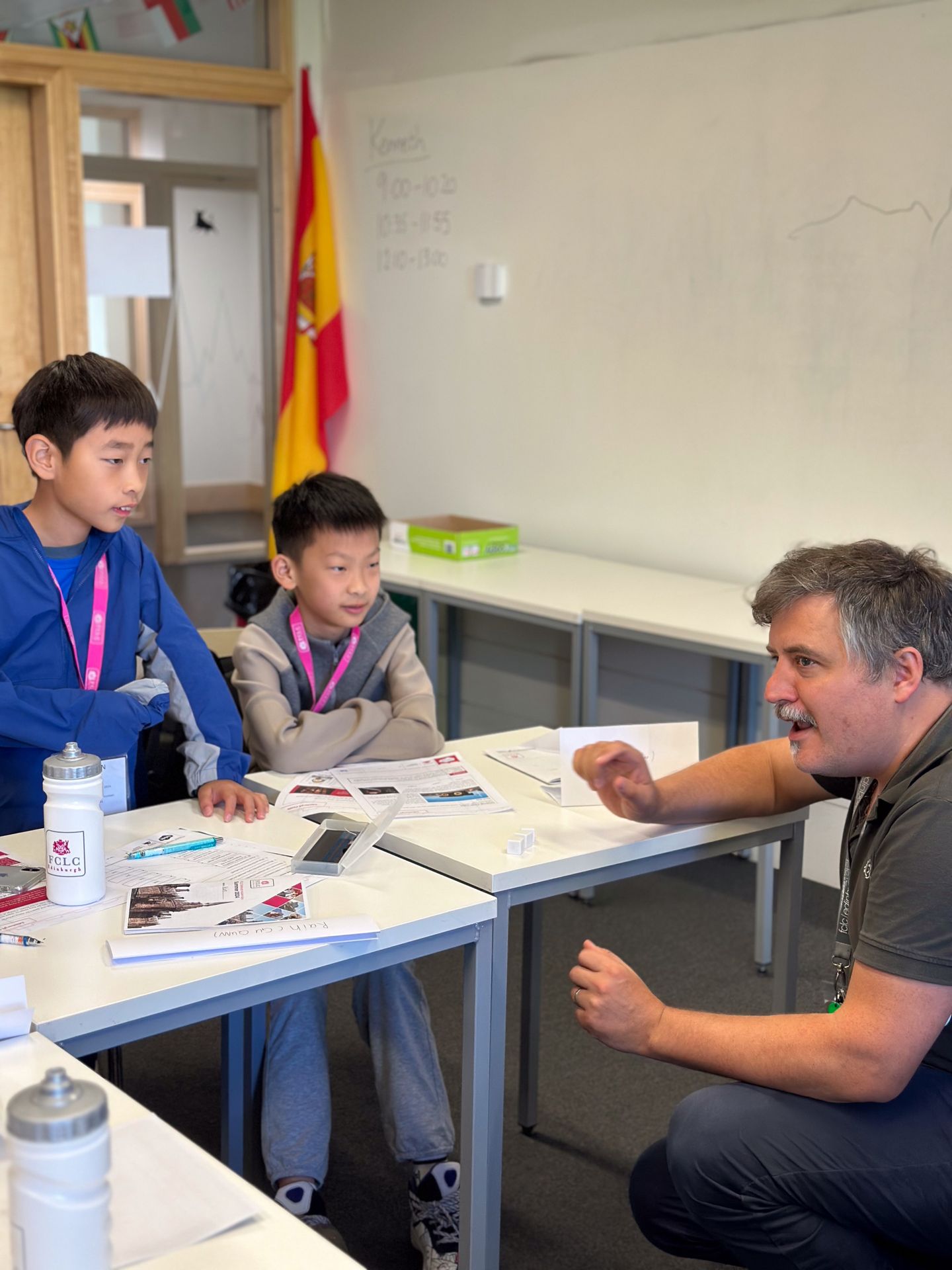 Image of teacher on right explaining something to a student off frame with two other students on left frame listening