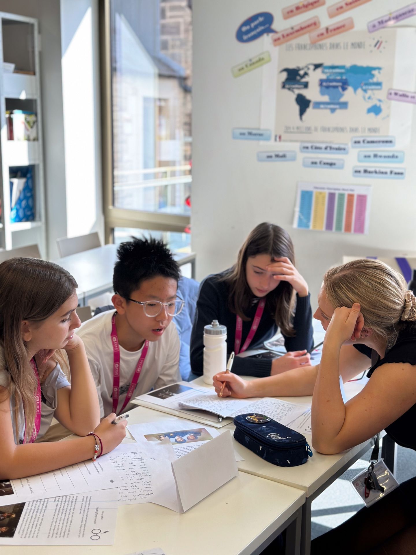 Image of teacher on right of frame explaining something to 3 students on the right of frame